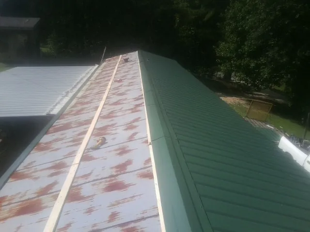 Old rusted panels beside newly installed green metal roofing — Wind Damage Roof Repair by Roofing Brothers in Torrey