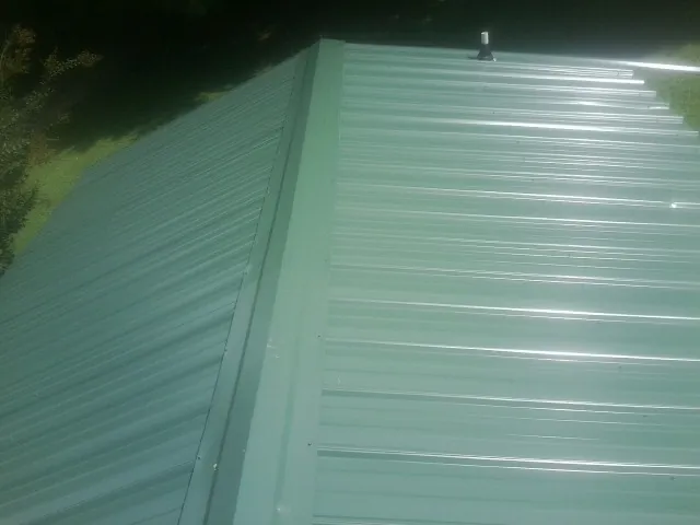 New green metal panels meeting at the ridge of a roof — Flat Roof Repair work by our crew in Torrey