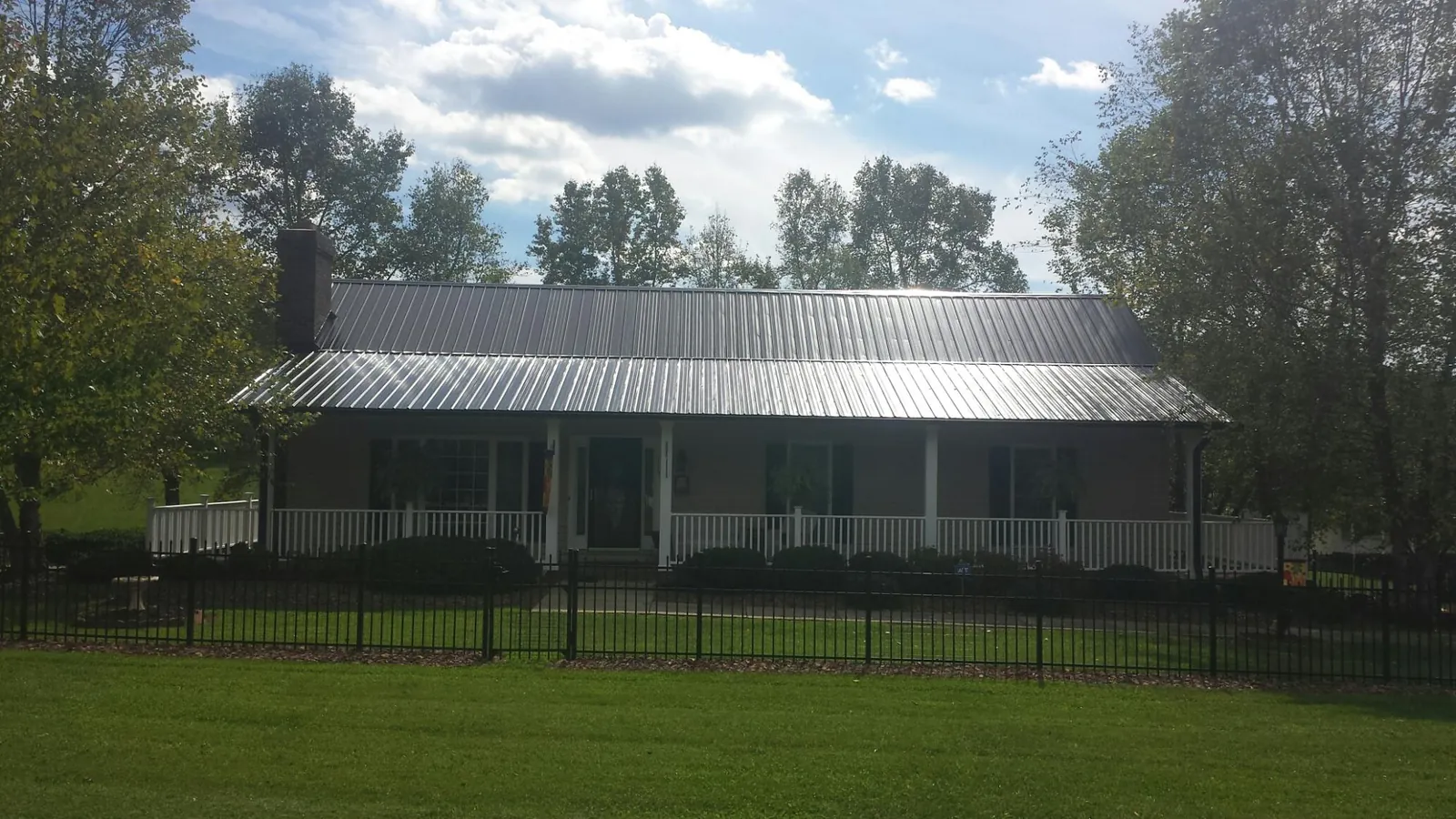 Gray metal roof on a brick ranch with a full width front porch — Gutter Guard Installation work by our crew in Torrey