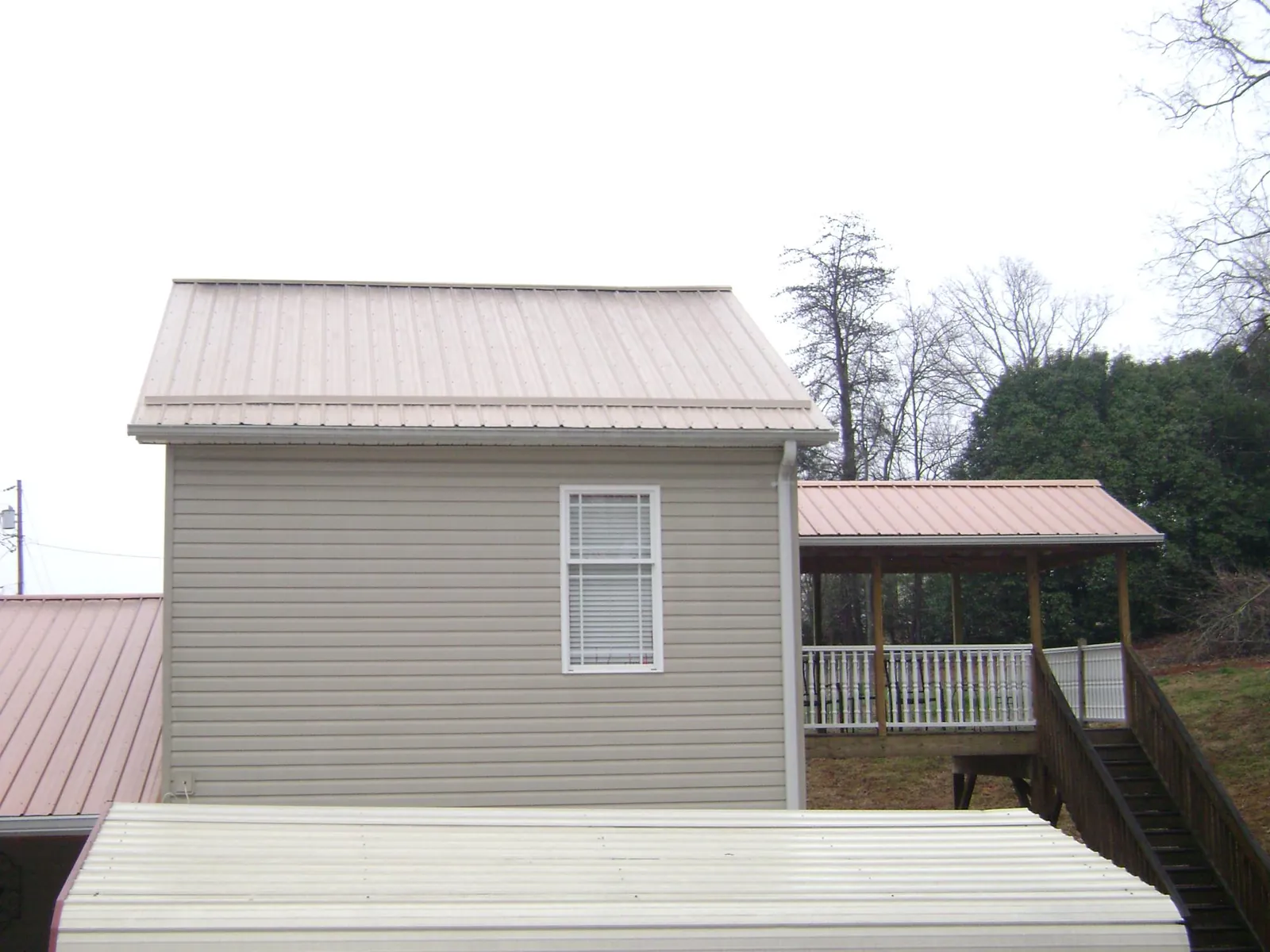 Tan metal roofs on a two story addition and attached porch, from a Roof Replacement job in Torrey