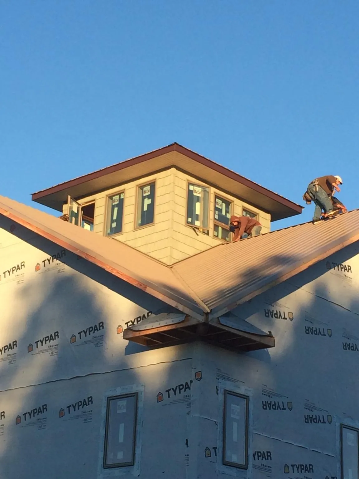 Roofers working around a rooftop cupola on a new metal roof at sunset — Roof Waterproofing in Torrey by Roofing Brothers